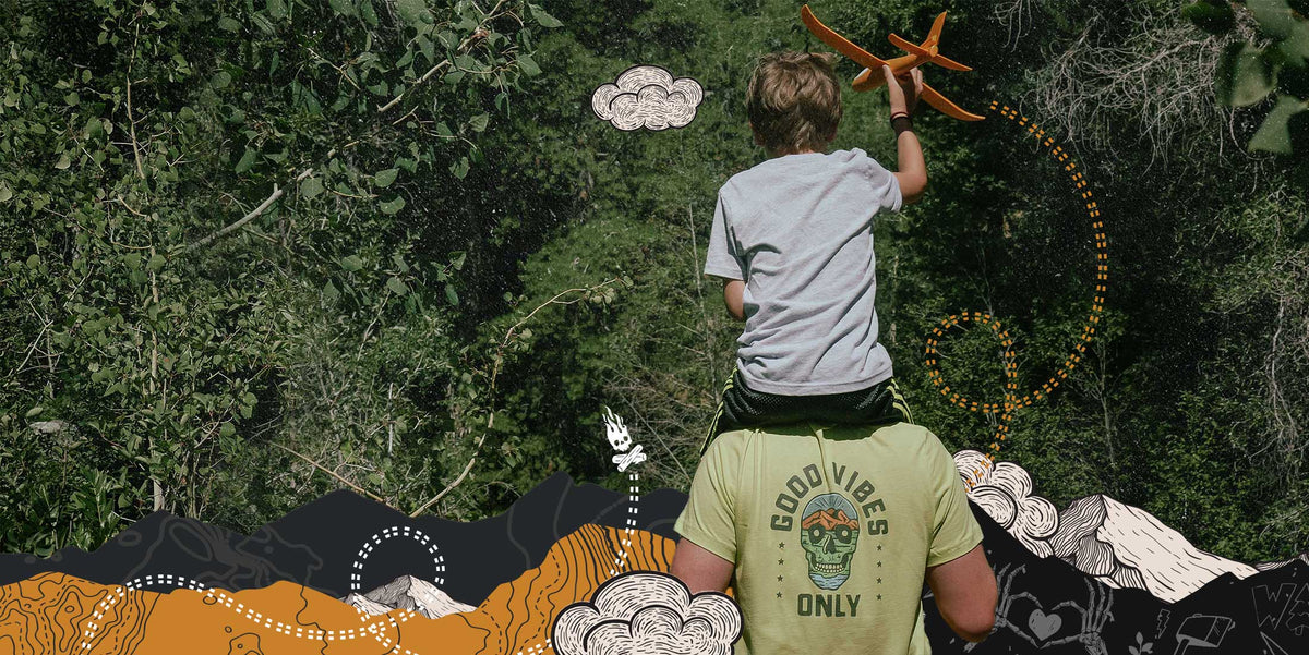 Milk x Whiskey - Good Vibes Only Tshirt. A father with his child on his shoulders on a trail with a toy airplane.