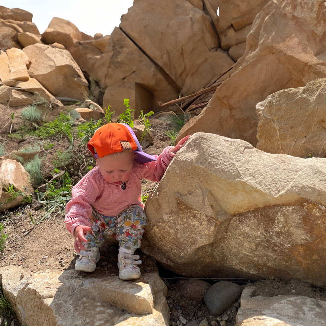 a baby exploring in the wild outdoors with milk x whiskey baby adventure hat.