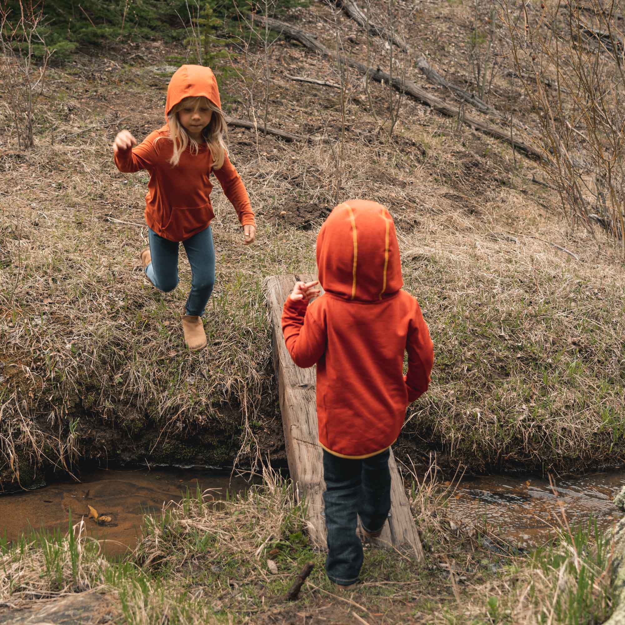 Kids wearing orange sun hoodies playing outdoors, showcasing UPF 50+ protection and eco-friendly material for toddler sun safety.