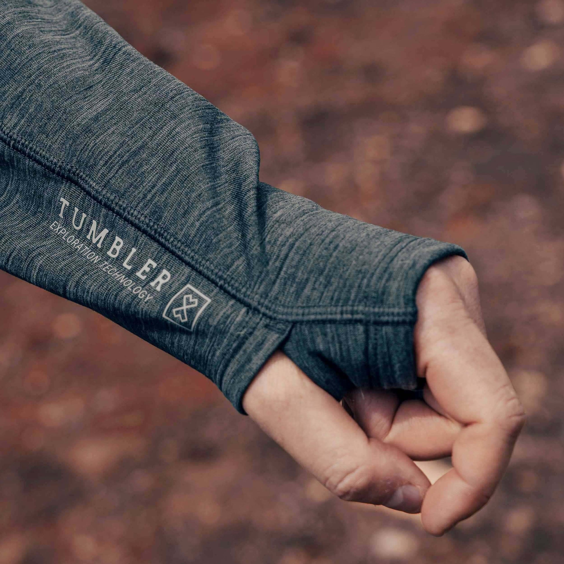 Close-up of a hand wearing a Tumbler Grid Fleece Hoodie during an outdoor activity, showcasing the thumbhole feature and material texture.