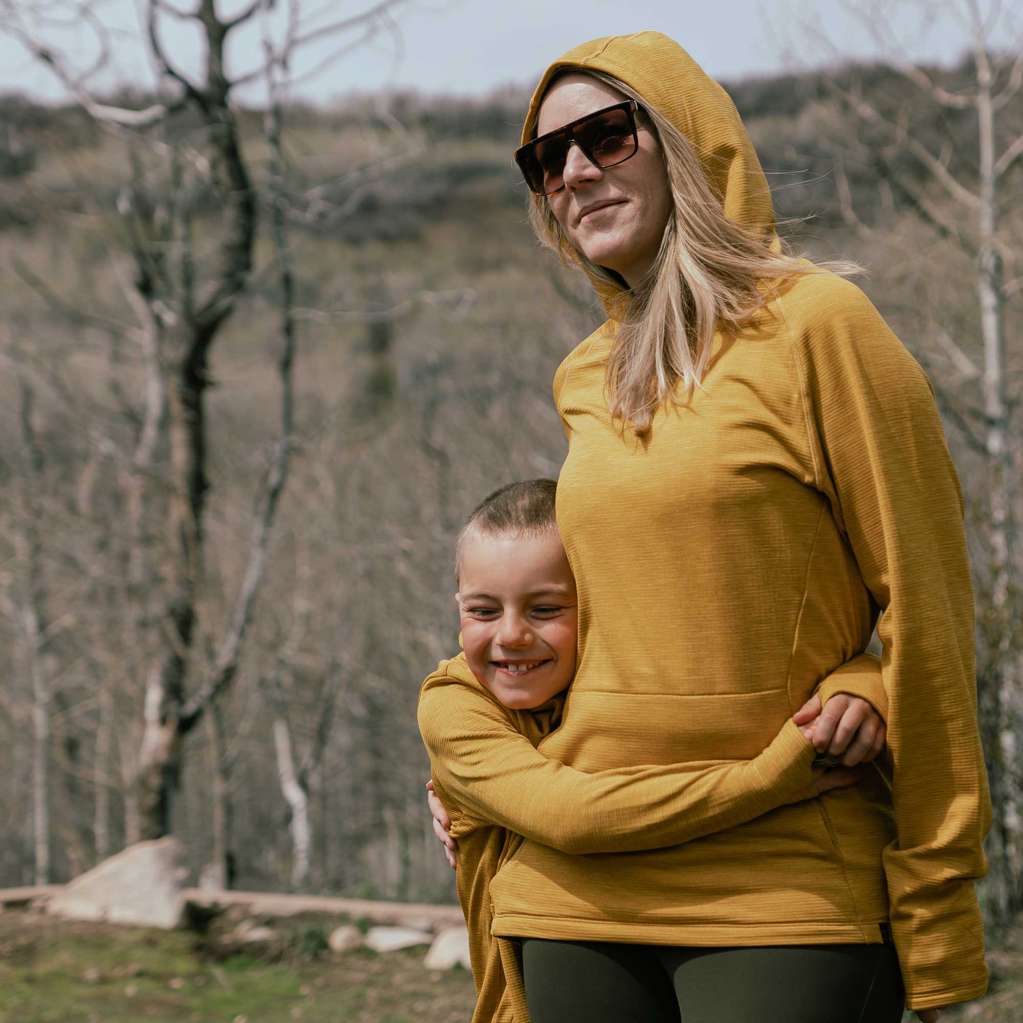 Woman and child wearing yellow grid fleece hoodies outdoors in nature.